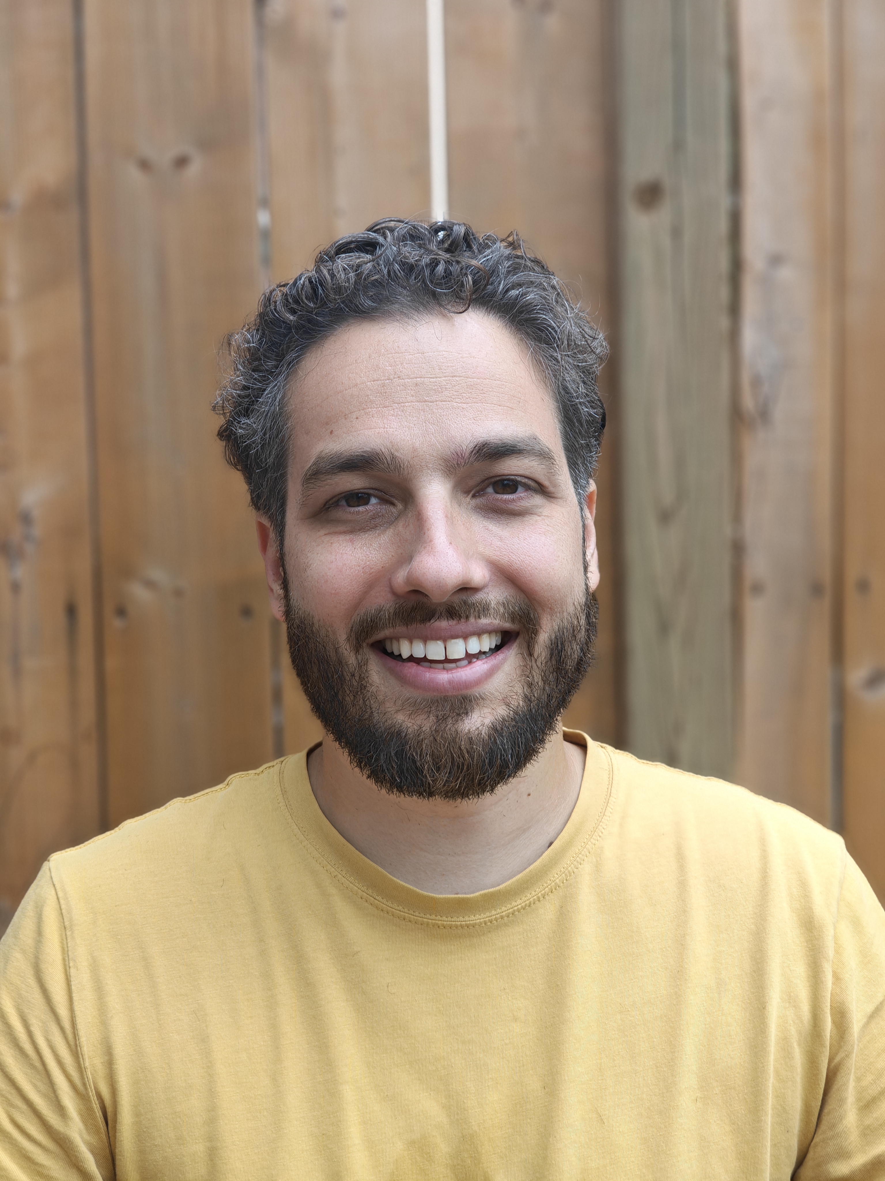 Chris Staikos smiling, wearing a yellow shirt